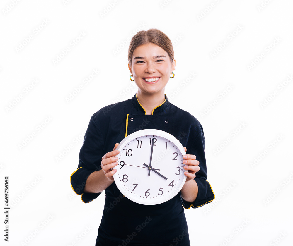 Photo of beautiful woman chef, wearing uniform smiling at camera and holding a clock Photo of beautiful woman chef, wearing uniform smiling at camera and holding a clock