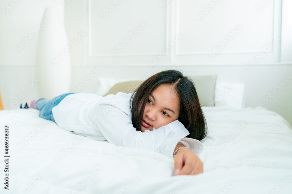 Portrait Cute Asian teen with long hair Wearing a white shirt and lazing around in bed happily in the bedroom. Portrait Cute Asian teen with long hair Wearing a white shirt and lazing around in bed happily in the bedroom.