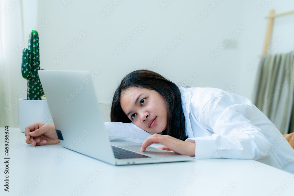 Portrait Cute Asian teen with long hair Wearing a white shirt, sitting online studying with a laptop on the bedroom table with a thoughtful face. Portrait Cute Asian teen with long hair Wearing a white shirt, sitting online studying with a laptop on the bedroom table with a thoughtful face.