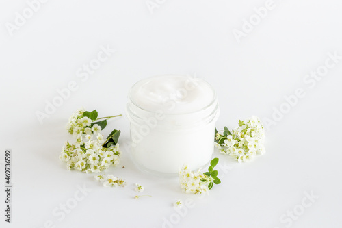 White blossoms flowers with skin cream in glass jar