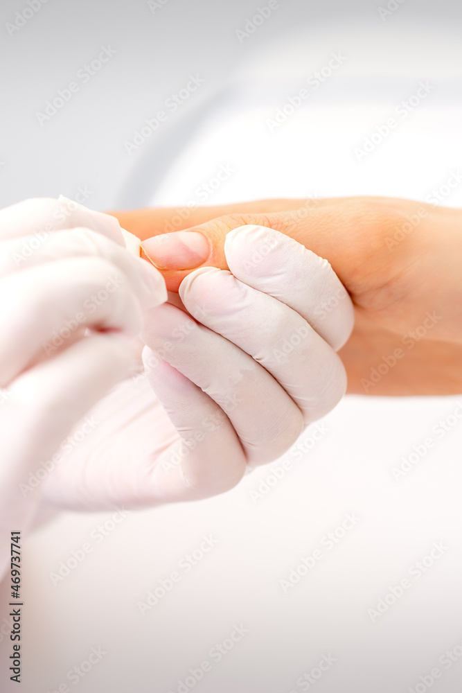 Naklejka premium Manicure master wiping the moisturizer from the end of female fingers in beauty salon