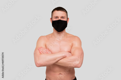 Sportsman Wearing Medical Mask. Man Hands Crossed with Mask. Healthy Life, Medical protection, Sports Concept. Man Standing Topless