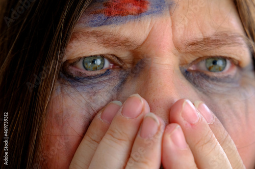 close-up of hand at female tear-stained face, beaten woman with bruises and abrasions, quiet cry for help, concept of domestic violence, emotion of suffering from pain, kidnapping, being in danger