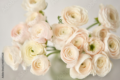 The background of ranunculus colors is gently pink. A riotous peony-shaped rose bouquet