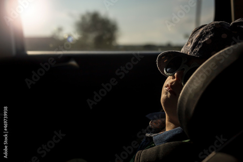 Boy napping in car seat with sunglasses on photo