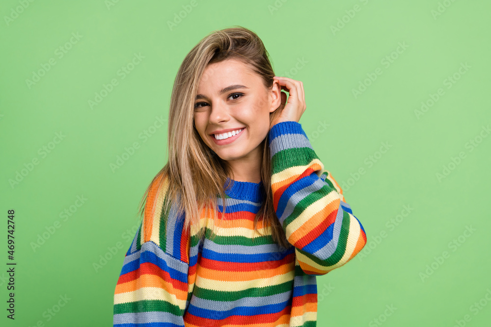 Photo portrait girl touching hair smiling wearing striped sweater isolated pastel green color background Photo portrait girl touching hair smiling wearing striped sweater isolated pastel green color background