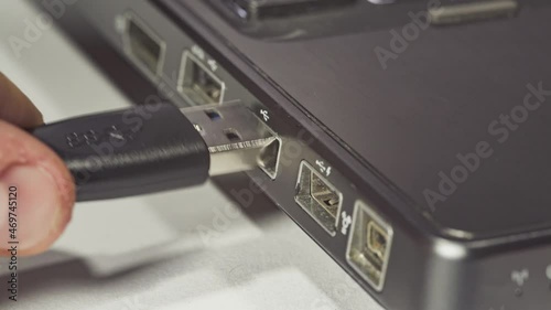 Close up of hand inserting plugging data cable into usb port in laptop 3 photo