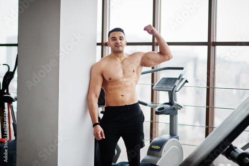 Muscular arab man in modern gym. Fitness arabian men with naked torso show his biceps.