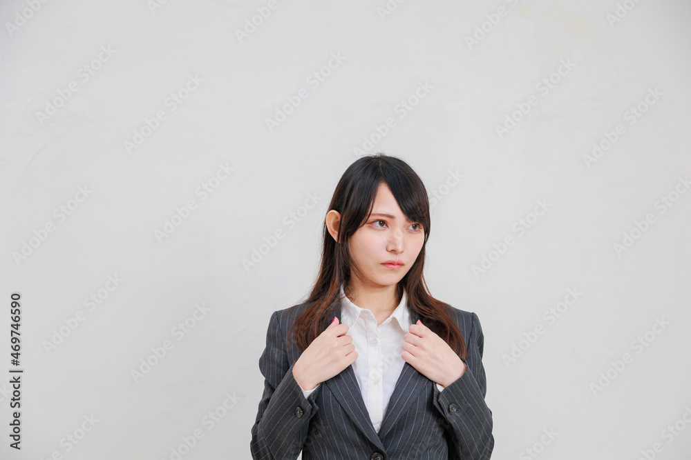 白背景の前に立つスーツを着たアジア人女性