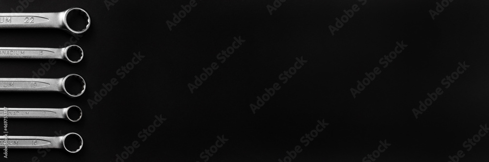 Steel closed end ring wrenches on black background. Wide panoramic banner with copy space