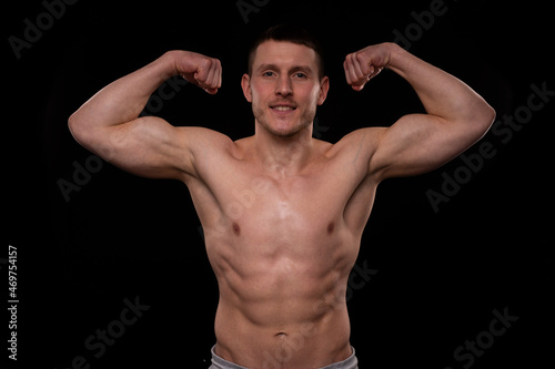 Man Showing Biceps Hands Up. Sportsman Showing Muscles. ABS, Biceps Muscles. Black Background