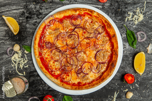 Fresh pizza with a ton on wood background