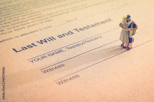 Fotografia Last will and testament / legacy, inheritance or death tax concept : Miniature elder couple stands on a legal document form
