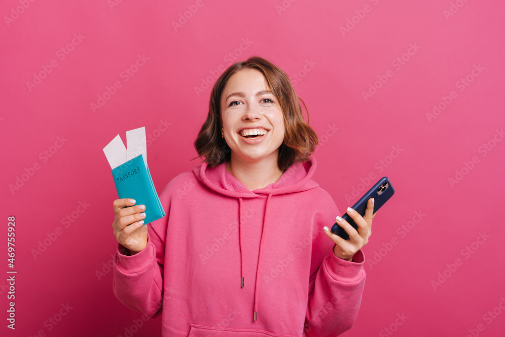 Joyful young smiling woman holding passport with tickets and smartphone, ready for travel. Joyful young smiling woman holding passport with tickets and smartphone, ready for travel.