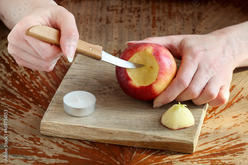 Woman shows how to make a Christmas decoration with apple, candle and branches of fir photo