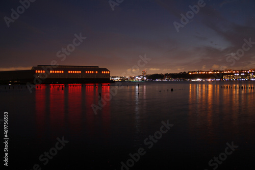 An industrial night shot with the pier and the light behind the river
