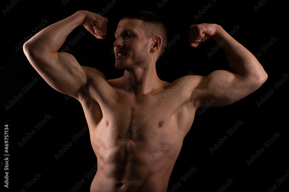 Man Showing Biceps Hands Up. Sportsman Showing Muscles. ABS, Biceps Muscles. Black Background. Topless Man Looking to Side Man Showing Biceps Hands Up. Sportsman Showing Muscles. ABS, Biceps Muscles. Black Background. Topless Man Looking to Side