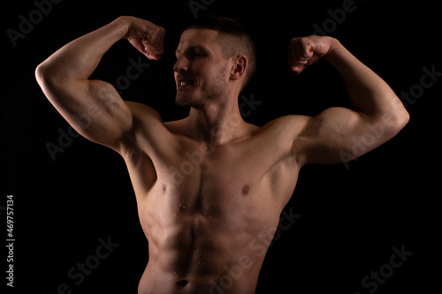 Man Showing Biceps Hands Up. Sportsman Showing Muscles. ABS, Biceps Muscles. Black Background. Topless Man Looking to Side