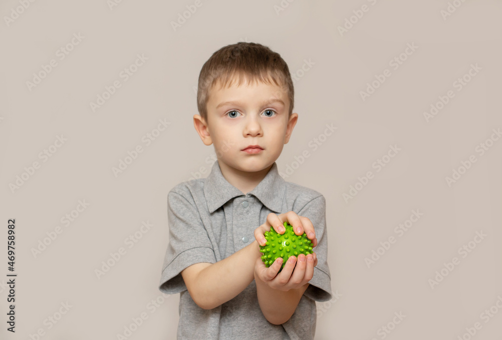 The child performs an exercise with a relief ball the development of tactile sensations. An exercise for of fine motor skills of the hands. Child health concept. Selective focus The child performs an exercise with a relief ball the development of tactile sensations. An exercise for of fine motor skills of the hands. Child health concept. Selective focus