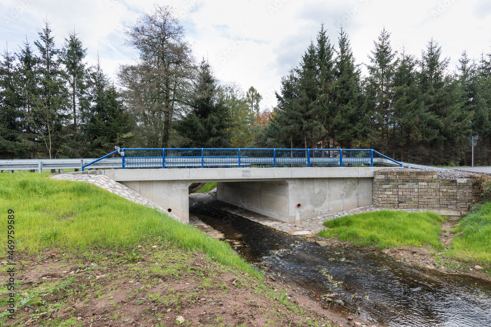 A new bridge across a small river. Summer time. Small reinforced concrete bridge after reconstruction. New asphalt.