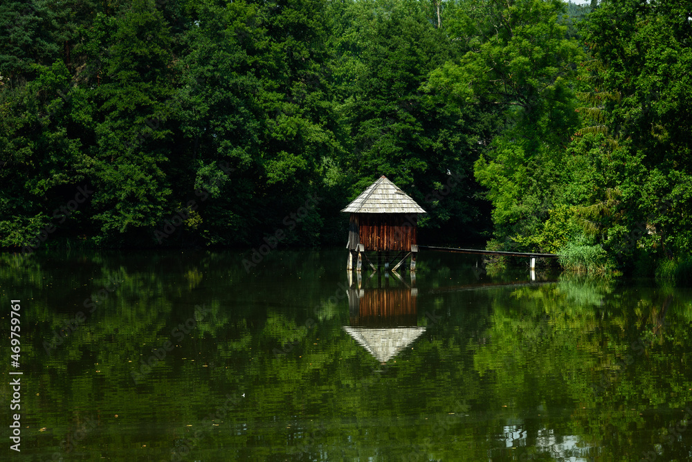Obraz premium Wooden cabin in the calm water of a pond, Hallegg, Austria
