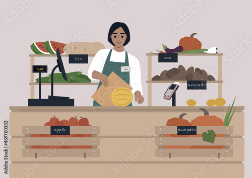 A young female Caucasian cashier at the farmers market, fruits and vegetables in wooden crates