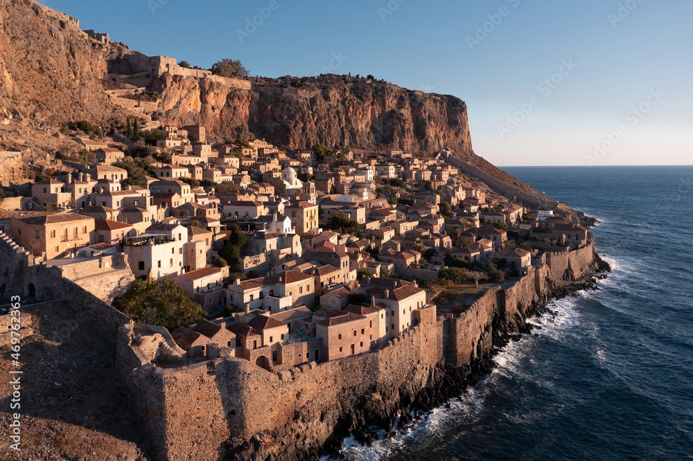 Aerial view of Monemvasia ancient town behind fortress wall on a shore of big island at sunrise