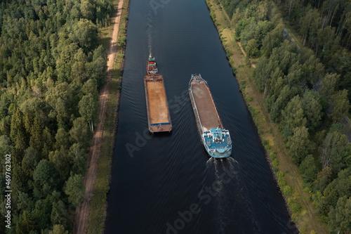 Aerial view of two barges diverging along a narrow channel in opposite directions