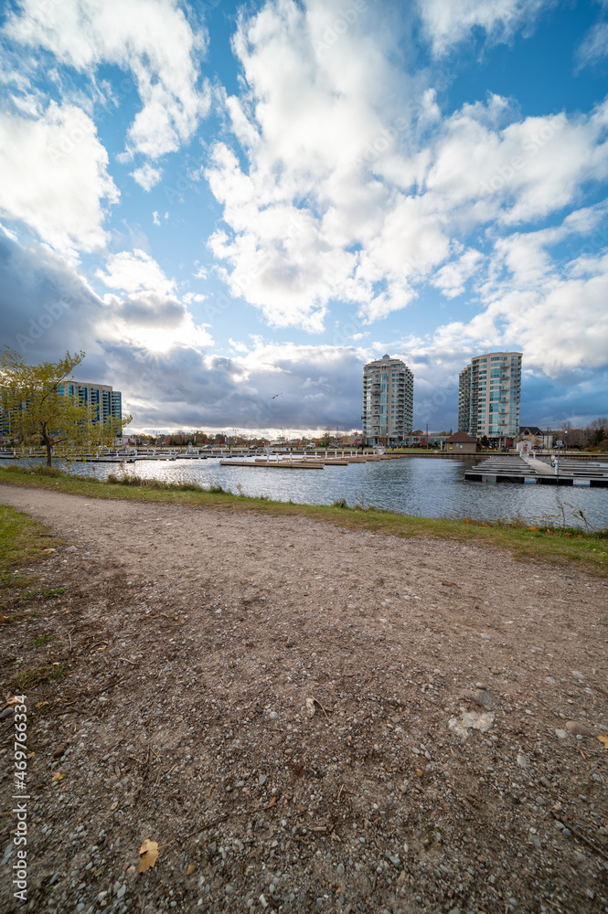 Barrie waterfront centennial park  lake shore  path with green grass and fall colour trees   blue sky with broken clouds 