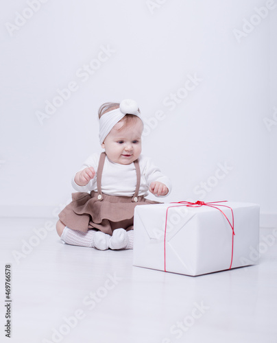 A beautiful, elegant girl received a gift. In a bright studio, a child plays and opens a gift..A picture of baby girl with big gift box