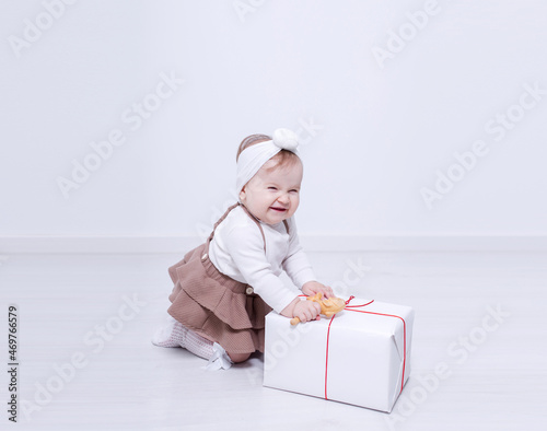 A beautiful, elegant girl received a gift. In a bright studio, a child plays and opens a gift..A picture of baby girl with big gift box