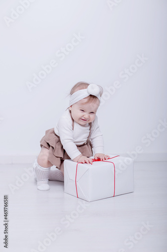A beautiful, elegant girl received a gift. In a bright studio, a child plays and opens a gift..A picture of baby girl with big gift box