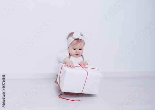 A beautiful, elegant girl received a gift. In a bright studio, a child plays and opens a gift..A picture of baby girl with big gift box