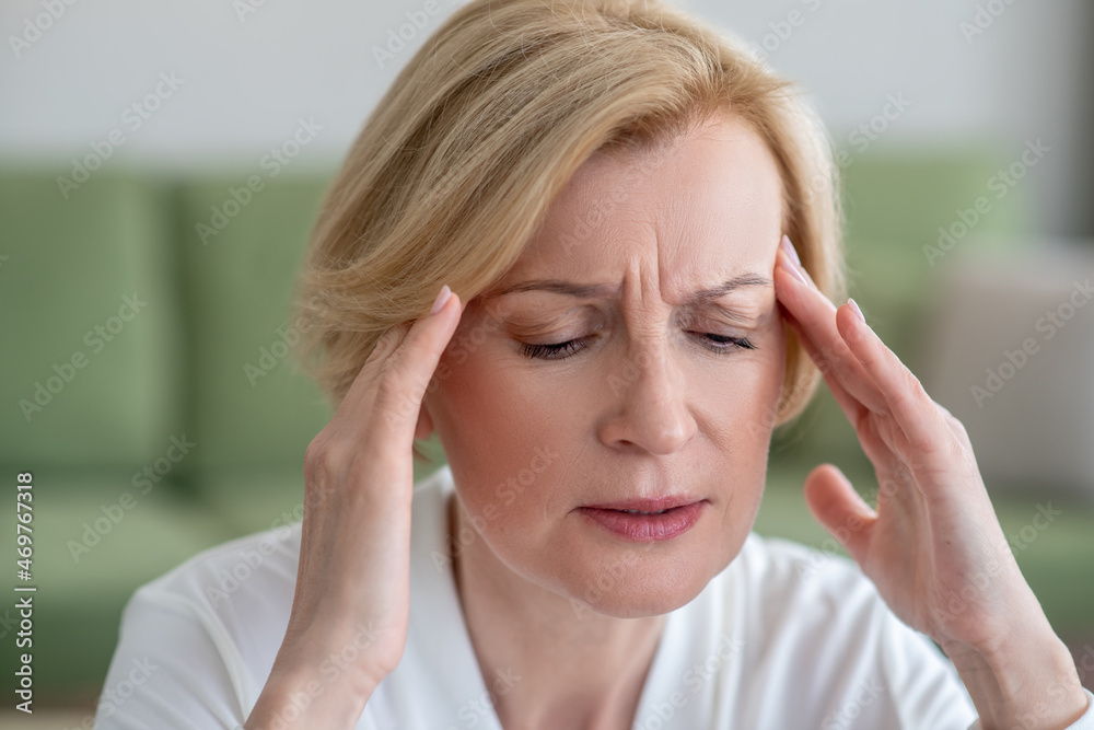 Midaged blone woman suffering from a headache Midaged blone woman suffering from a headache