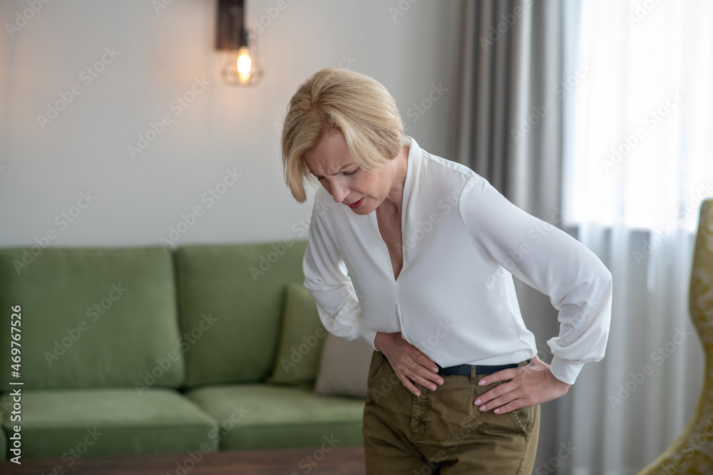 Blond woman feeling bad while suffering from a stomachache Blond woman feeling bad while suffering from a stomachache
