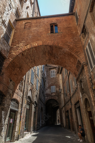 Narrow Street in Historic Center of Siena  Tuscany  Italy. Old brick and stucco houses  arches and cobblestone pavement