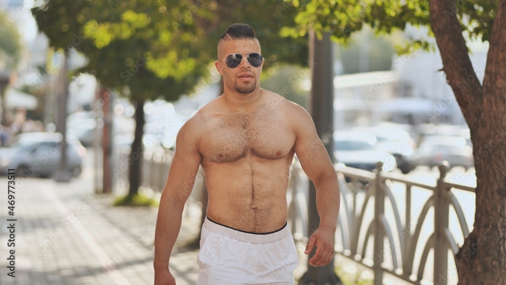 A muscular Jordanian man walks around the city without a shirt.