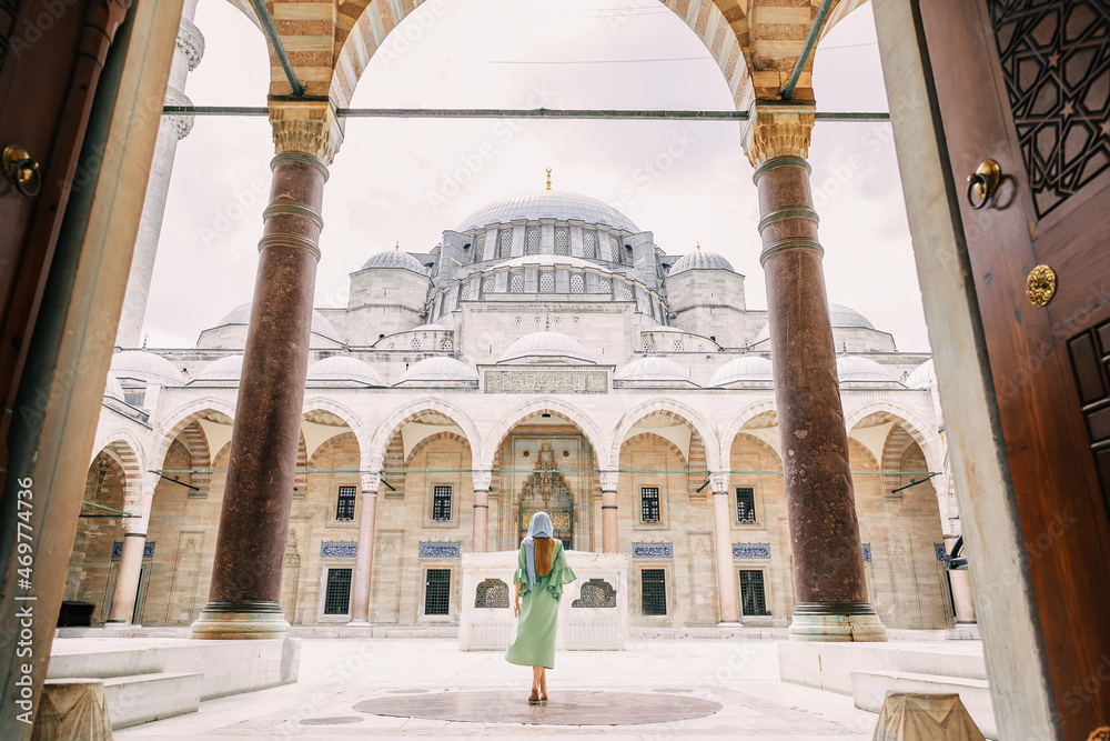 A young girl in a headscarf goes to a Suleymaniye Mosque mosque in Istanbul. Summer vacation, travel. Rear view of a slender girl with long hair, in a dress