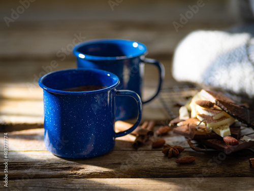 Cozy warm composition - on a wooden background, two cups of coffee, many pieces of chocolate and almonds. Delicious family breakfast, romantic evening, holiday atmosphere.