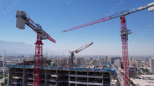 Huge Red Tower Cranes at a Construction Site Overlooking the City in Santiago, Chile. Drone View. 4K Resolution. photo