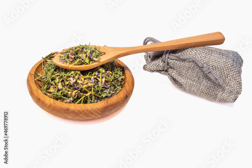 Astragalus (Astragalus membranaceus) in a wooden dish. Nearby is a canvas bag with dry medicinal herbs.