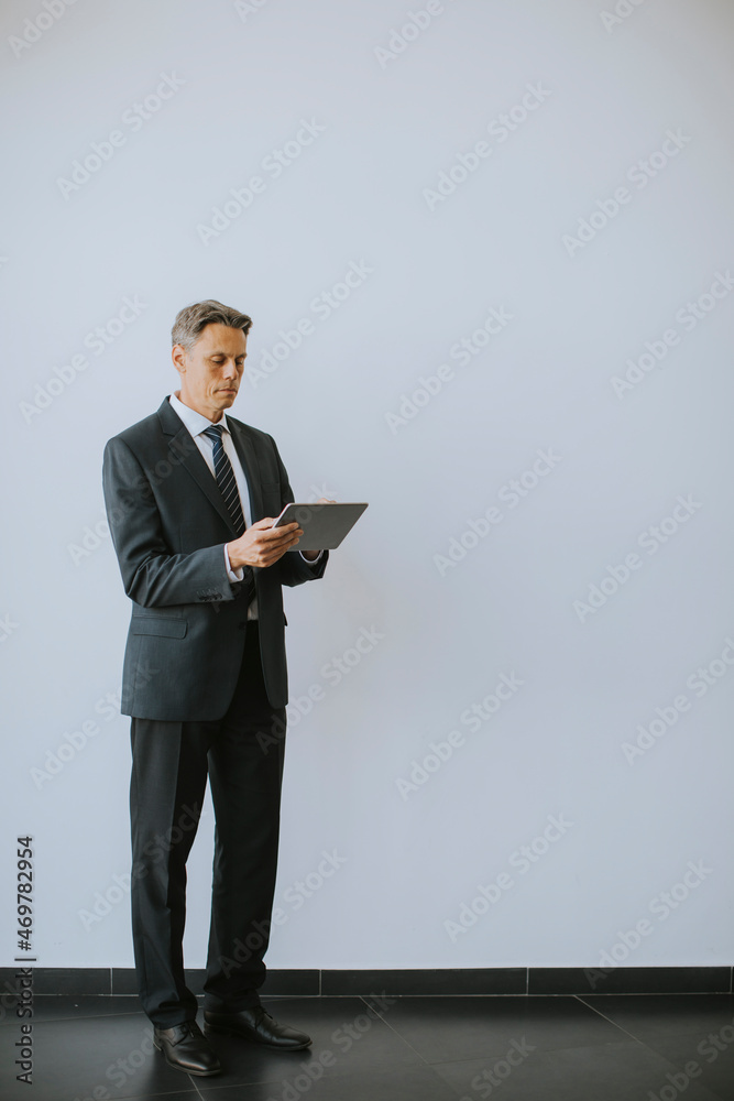 Business man using digital tablet by the wall in the office Business man using digital tablet by the wall in the office