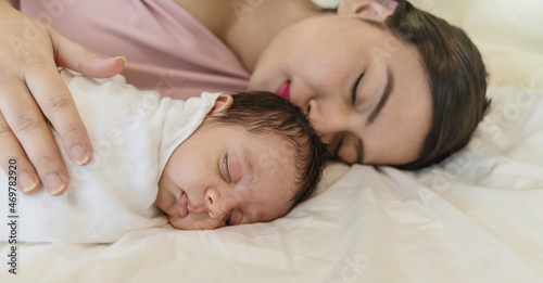 Close up portrait of beautiful young asian mother with her newborn baby, copy space with bed in the hospital background. Healthcare and medical love, lifestyle Indian Arab mother's day concept