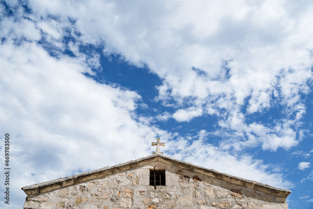 The top of the church with a cross against a bright blue sky. Part of the temple is made of white stone. Minimalist frame of architecture. Pure colours
