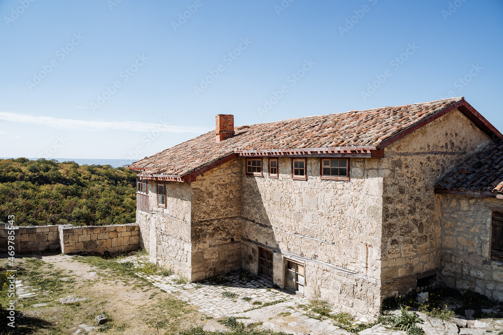 Old house with a tiled roof in the mountain plains. Large stone house. Bright blue sky, clear mountain air and green forests. Rest in the mountains