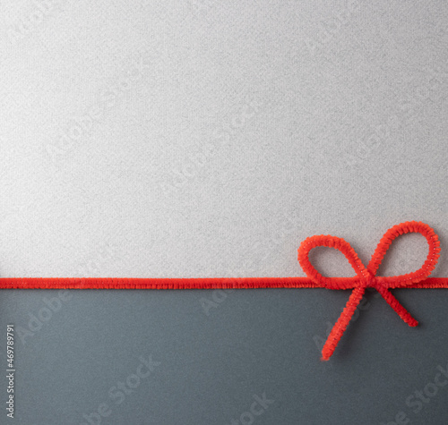 The minimal Concept is a combination of a dark
and light gray background separated by a red decorative ribbon with a bow. A greeting card. free space for signature. Top view.