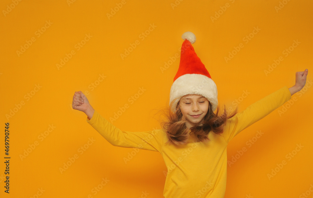 Emotional cute little girl in santa hat on yellow background with a copy space. Emotional cute little girl in santa hat on yellow background with a copy space.