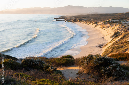 View from the cliffs over the sandy beach and waves breaking on shore.  