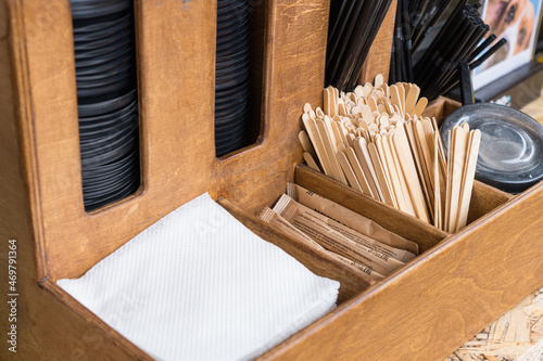 A set for self-service in a cafe. Caps for coffee cups, napkins, sugar and wooden sticks in a wooden box