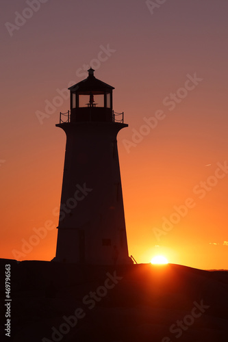 Silhouette shot of the Peggy's Cove Lighthouse during a beautiful sunset full of red and orange sky as the sun sets behind the horizon. Peggy's Cove Lighthouse, Halifax, Nova Scotia, Canada